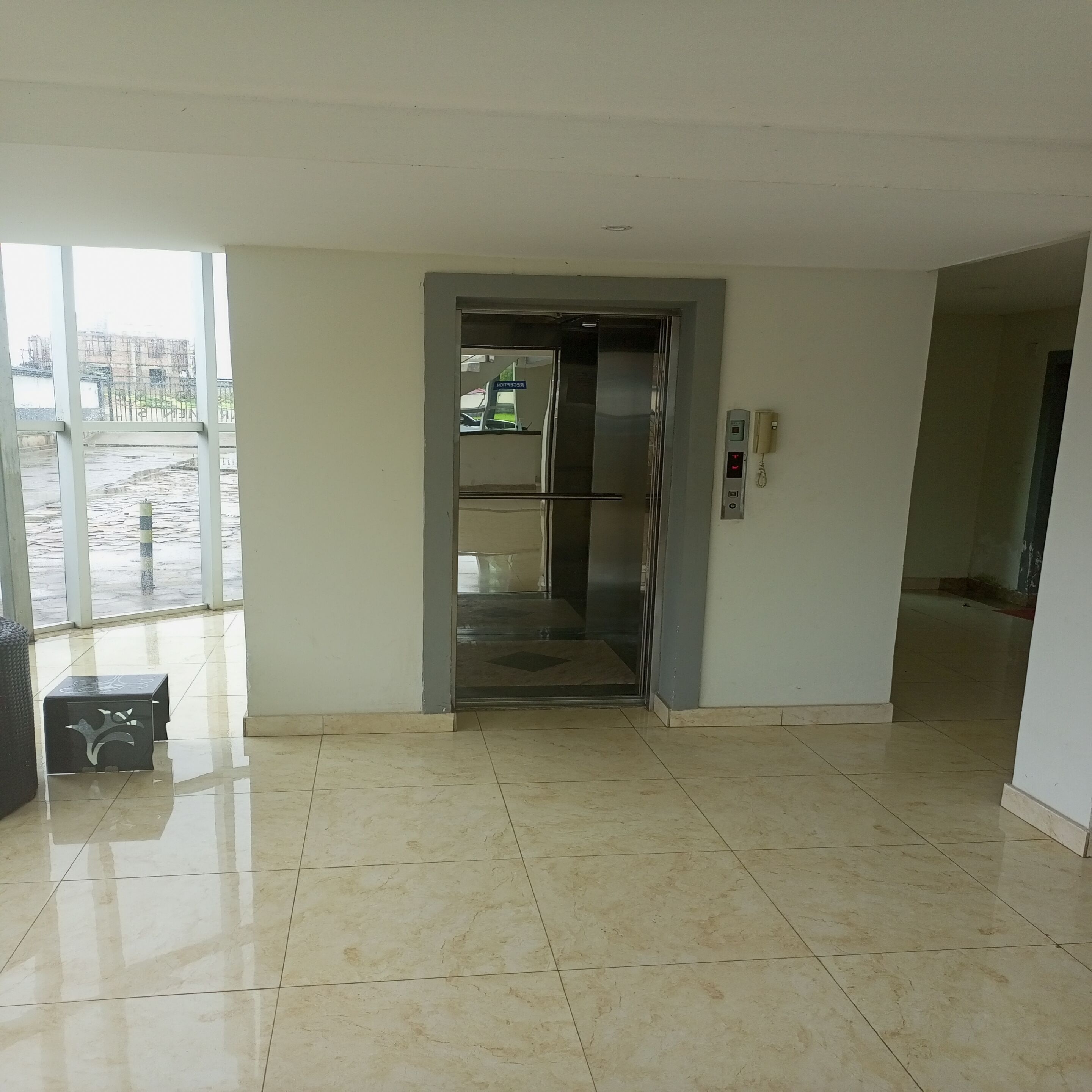 A corridor with a shiny tiled floor leading to an elevator.