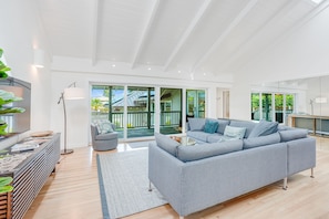 Een ruime woonkamer met een grijze bank, een salontafel en een grote schuifglazen deur die uitkomt op een balkon.