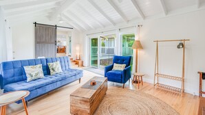 Een ruime woonkamer met een blauwe bank, een houten salontafel en een blauwe fauteuil.