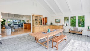 Een ruime keuken met een houten eettafel en bank, een inbouwkast en een groot raam dat voor natuurlijk licht zorgt.