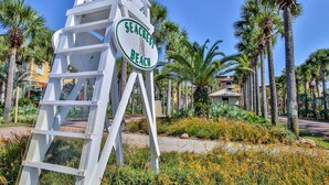 Un panneau indiquant l’accès à la plage de Seacrest, entouré de palmiers et bordé d’un sentier.