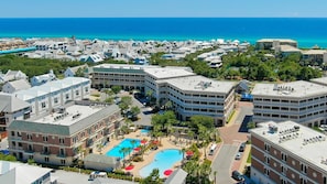 A resort with multiple buildings, a central pool area, and a view of the ocean.