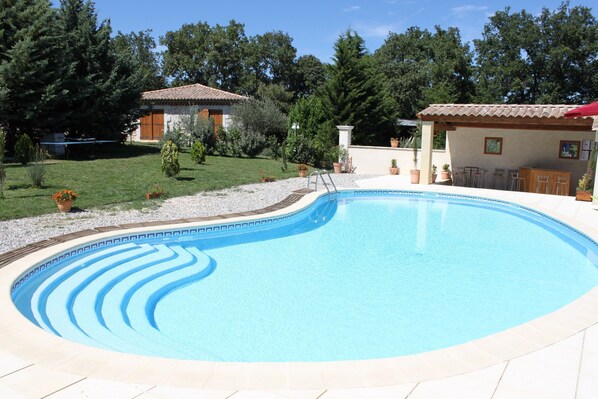 Relax by the pool surrounded by a serene garden and a charming building.