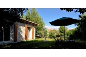 Relax in a serene outdoor setting with a charming building, lawn, and patio area.