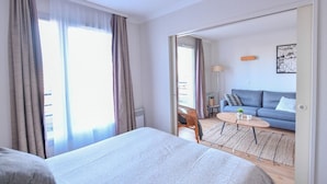 Habitación de hotel con cama, sofá, una mesita y vistas al exterior.