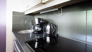 Una cocina con estufa negra, cafetera y hervidor.