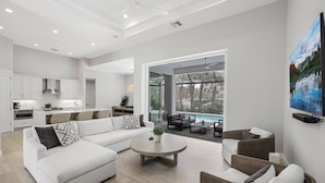 Un soggiorno moderno con un divano componibile, un tavolino da caffè e una zona pranzo con vista piscina.