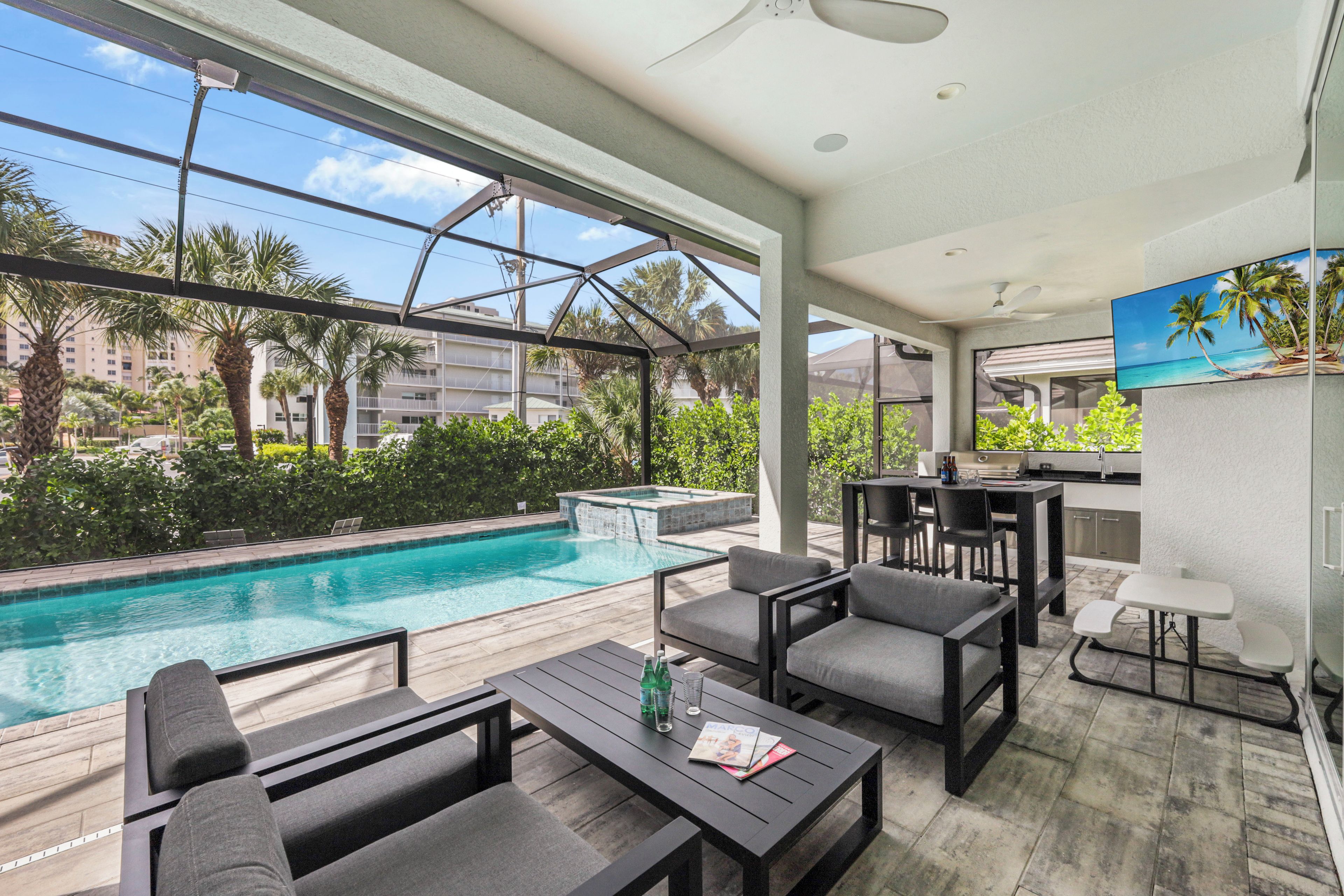 A poolside area with a pool, outdoor seating, and a kitchen area.