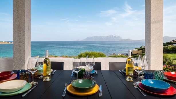 A table set for dining with a view of the sea and mountains.