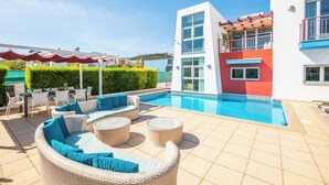 Zona de piscina exterior moderna amb mobiliari de vimet i una piscina de color blau clar.