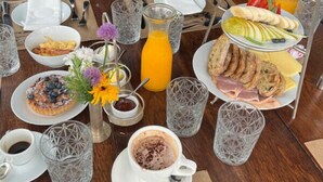 Un bufé de desayuno con diversos platos, una estación de café y una jarra de jugo.