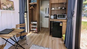 A compact kitchen with a microwave, refrigerator, and wooden cabinets. - "Timboon" Tiny House 10 - Escape @ Grampians' Edge (Dadswells Bridge)