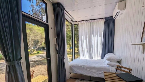 A bedroom with a bed, a desk, and a view of the outdoors. - "Timboon" Tiny House 10 - Escape @ Grampians' Edge (Dadswells Bridge)