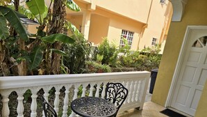 A balcony with a white balustrade, two black metal chairs, and a small round table. - Soufrière, St. Lucia 2BR Near Pitons Town Center Spacious + WiFi (Soufriere)