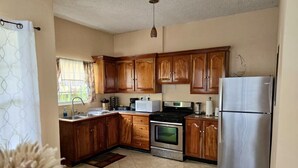 A kitchen with wooden cabinets, a stainless steel refrigerator, a stove, and a microwave. - Soufrière, St. Lucia 2BR Near Pitons Town Center Spacious + WiFi (Soufriere)