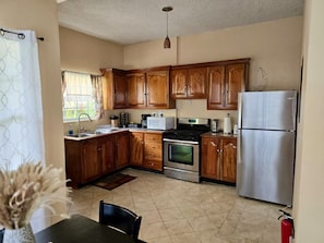 A kitchen with wooden cabinets, a stainless steel refrigerator, a stove, and a microwave. - Soufrière, St. Lucia 2BR Near Pitons Town Center Spacious + WiFi (Soufriere)