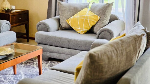 A living room with a sofa, a glass coffee table, and a side table with a lamp. - Soufrière, St. Lucia 2BR Near Pitons Town Center Spacious + WiFi (Soufriere)