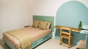 A bedroom with a bed, a desk, and a chair. - Chaim, Happiness to be where you should be. (Campeche)