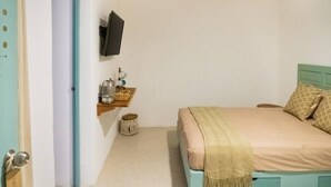 A bedroom with a bed, a TV mounted on the wall, and a small shelf with items. - Chaim, Happiness to be where you should be. (Campeche)
