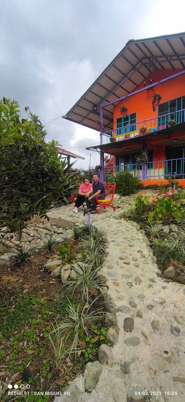 Un sendero conduce a una casa colorida con un porche cubierto y un camino de piedra.