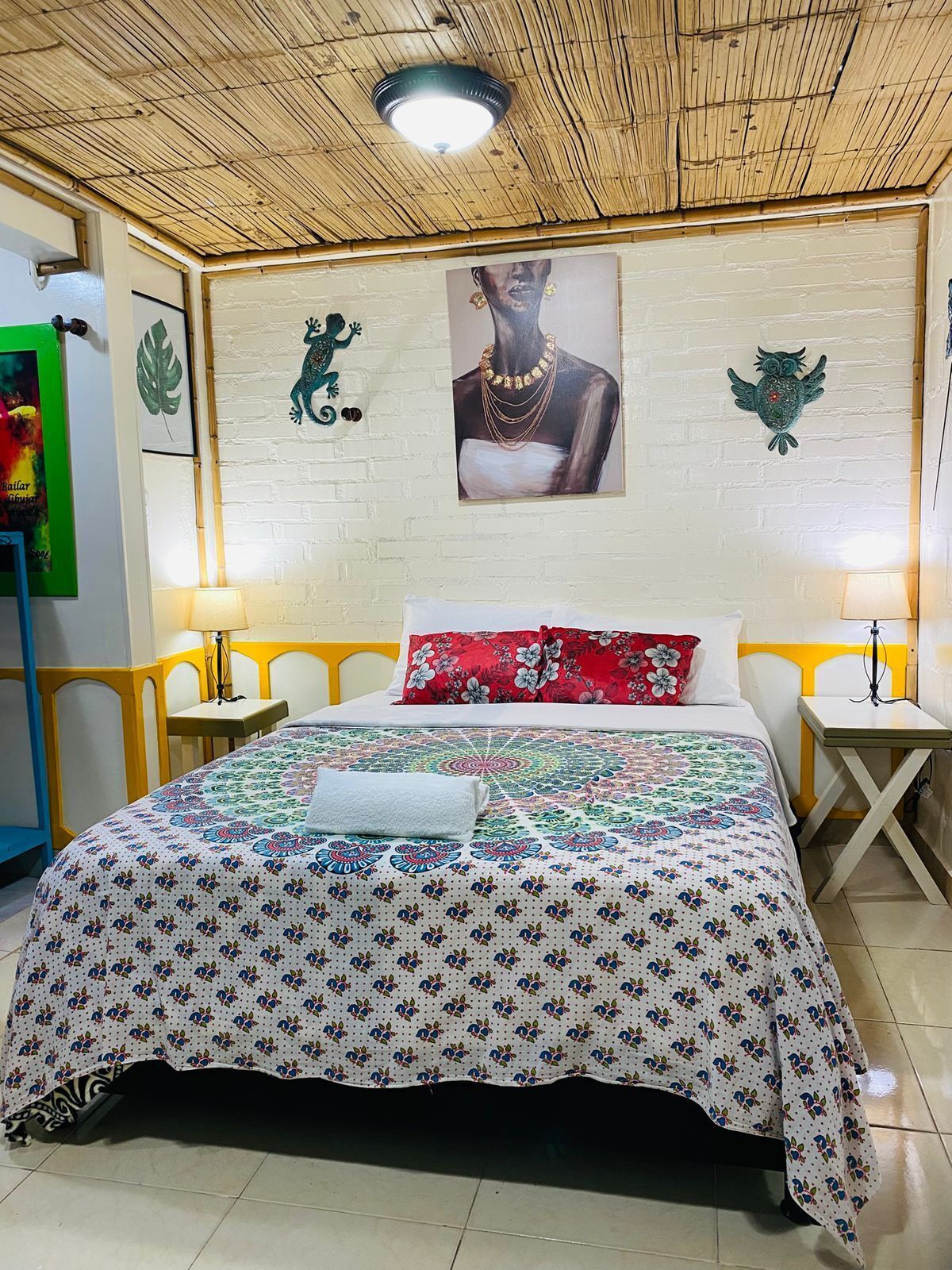 A room with a bed, two bedside tables, a wall-mounted picture, and a ceiling fan.