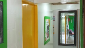 Un pasillo con una puerta amarilla, paredes blancas y un ventilador de techo.
