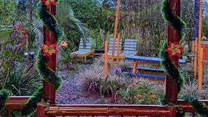 Un espacio al aire libre techado con un banco de madera, decorado con guirnaldas festivas y poinsettias.
