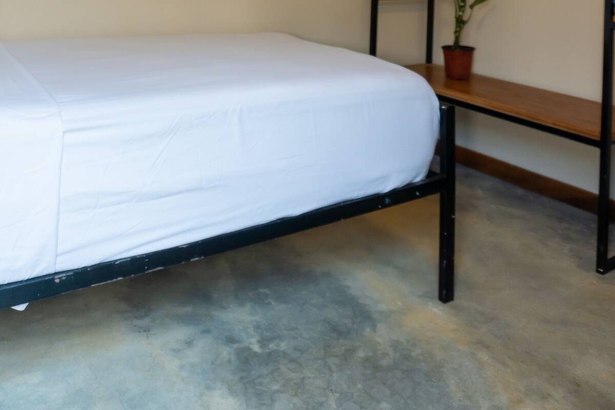 Ein Etagenbett mit weißer Matratze, einem Deckenventilator und einer Klimaanlage.