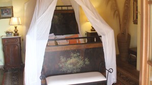 A room with a canopy bed, a bedside table with a lamp, a large vase, and a patterned rug. - Country house, lovingly renovated in the olive grove, large panoramic pool, air conditioning system (Caldana)
