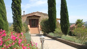 A stone pathway leading to a rustic stone house with a wooden door and steps. - Country house, lovingly renovated in the olive grove, large panoramic pool, air conditioning system (Caldana)