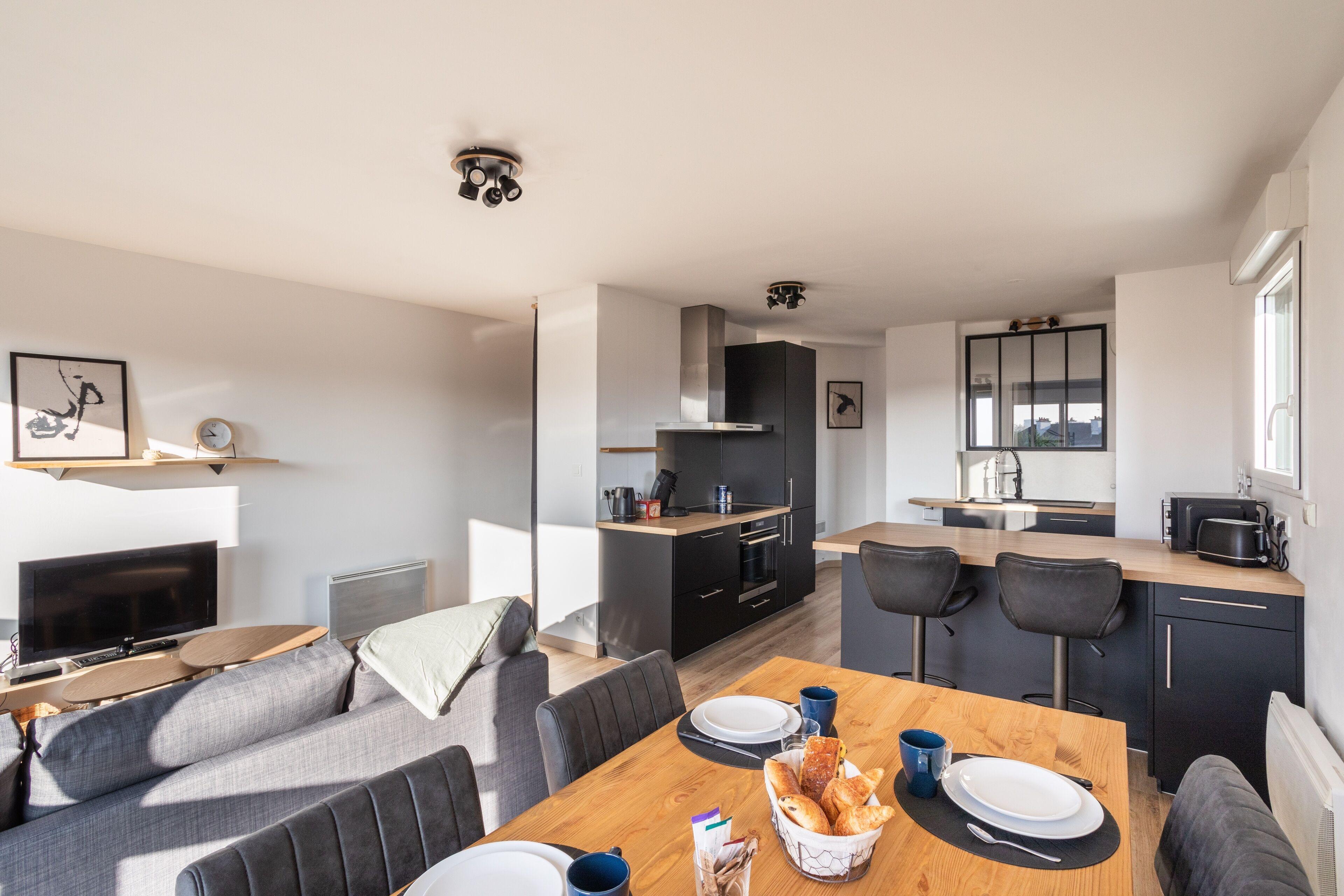 A modern living space with a dining area, kitchen, and seating area.