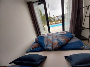 A bedroom with a large bed, a view of a swimming pool, and a balcony. - Hacienda MATEA – an oasis of romance near the beaches, Pula (Pula)