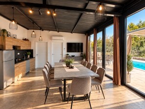 Cozinha moderna com área de jantar, grandes janelas e vista para a piscina.