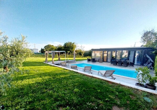 A swimming pool with lounge chairs, a covered seating area, and a glass-enclosed structure. - Hacienda MATEA – an oasis of romance near the beaches, Pula (Pula)