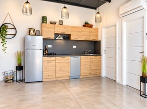 Eine moderne Küche mit Holzausstattung, einem Edelstahlkühlschrank und Pendelleuchten.