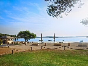 Une vue sur le lac, avec une terrasse en bois, des chaises longues et un petit bâtiment doté d’un toit.