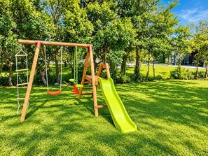 Ein Spielplatz mit Schaukeln und einer Rutsche.