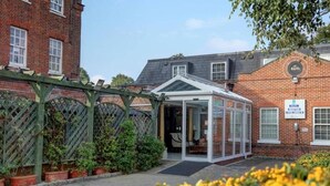 A hotel entrance with a glass door, a brick building, and a sign indicating hotel check-in. - Baylis Park Hotel (Slough)