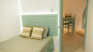 Ein kleines Schlafzimmer mit einem Bett, zwei Kissen und einer Tür zu einem Essbereich.