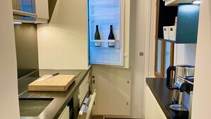 Une cuisine compacte équipée d’un four encastré, d’une machine à café et d’un réfrigérateur à vin.