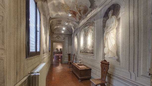 Un long couloir étroit, orné de décorations élaborées au plafond, avec un radiateur sur le côté gauche et un banc en bois sur le côté droit.