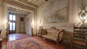 Une vaste pièce agrémentée d’un grand canapé richement décoré, d’un tapis à motifs et d’un grand tableau accroché au mur.