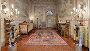 Une vaste pièce meublée avec goût, dotée d’un grand tapis et d’un lustre.