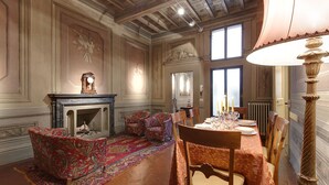 Une salle à manger avec une cheminée, des chaises à motifs, une table dressée pour quatre personnes et une grande fenêtre.