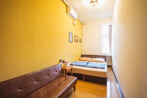 Una habitación pequeña y acogedora con una cama, un banco de madera y una ventana.