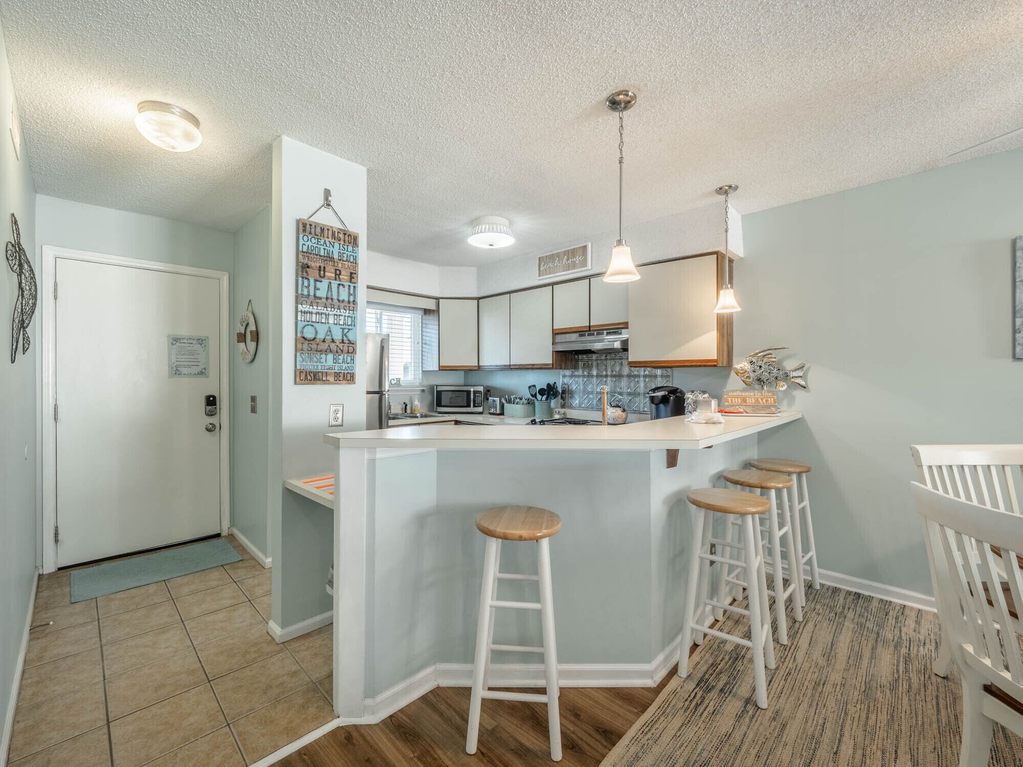 Una cocina moderna con una isla central, taburetes de bar y vistas al área de estar contigua.