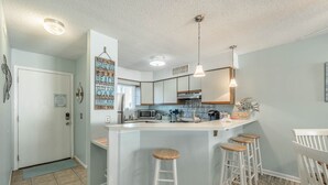 Een moderne keuken met een centraal eiland, barstoelen en uitzicht op de aangrenzende woonkamer.