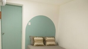 A bedroom with a bed, a wooden table, a patterned rug, and a door. - Shalom, The peace you need when traveling. (Campeche)