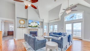 A spacious living room with a fireplace, a large sofa set, and a television. - Premier Oceanfront Home w/ Pool, Elevator, Hot Tub, Theater Room (Avon)