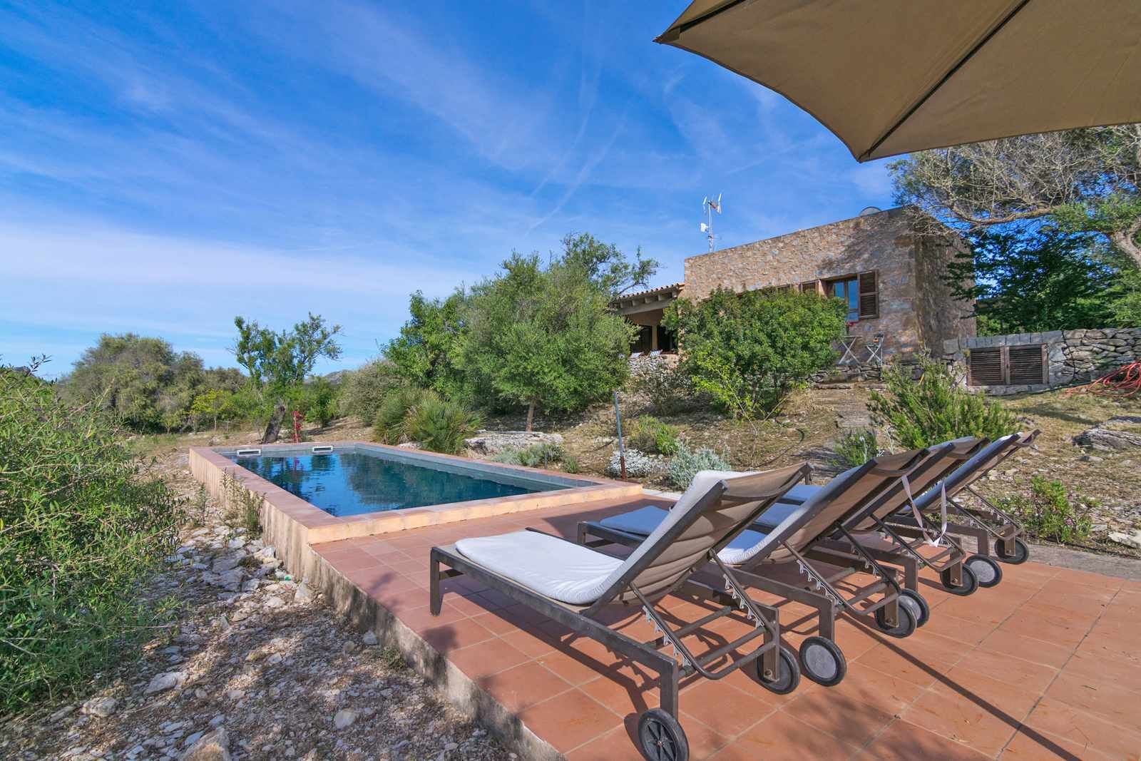 Una piscina amb gandules i un edifici de pedra al fons.